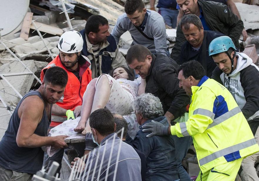 Rescuers help a woman from the rubble in Amatrice on August 24.