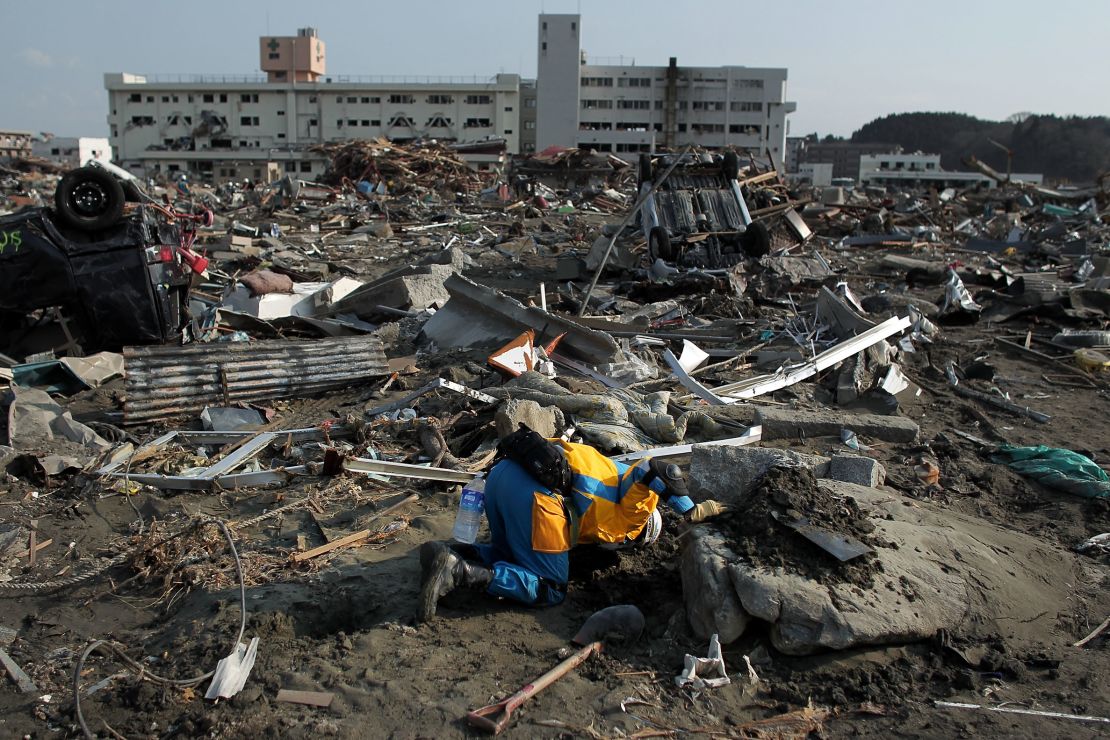 A rescue worker looks under a rock in Minamisanriku, Japan, after an earthquake and tsunami devastated the town. 