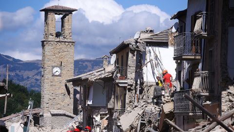 Firemen and rescuers inspect damaged buildings in Amatrice.