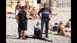 Police patrolling the promenade des anglais beach in Nice fine a woman for wearing a burkini on August 24, 2016.