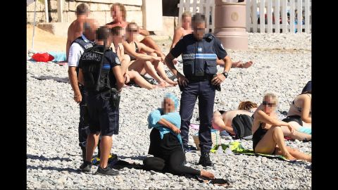 Police patrolling the Promenade des Anglais beach in Nice fines a woman for wearing a burkini.