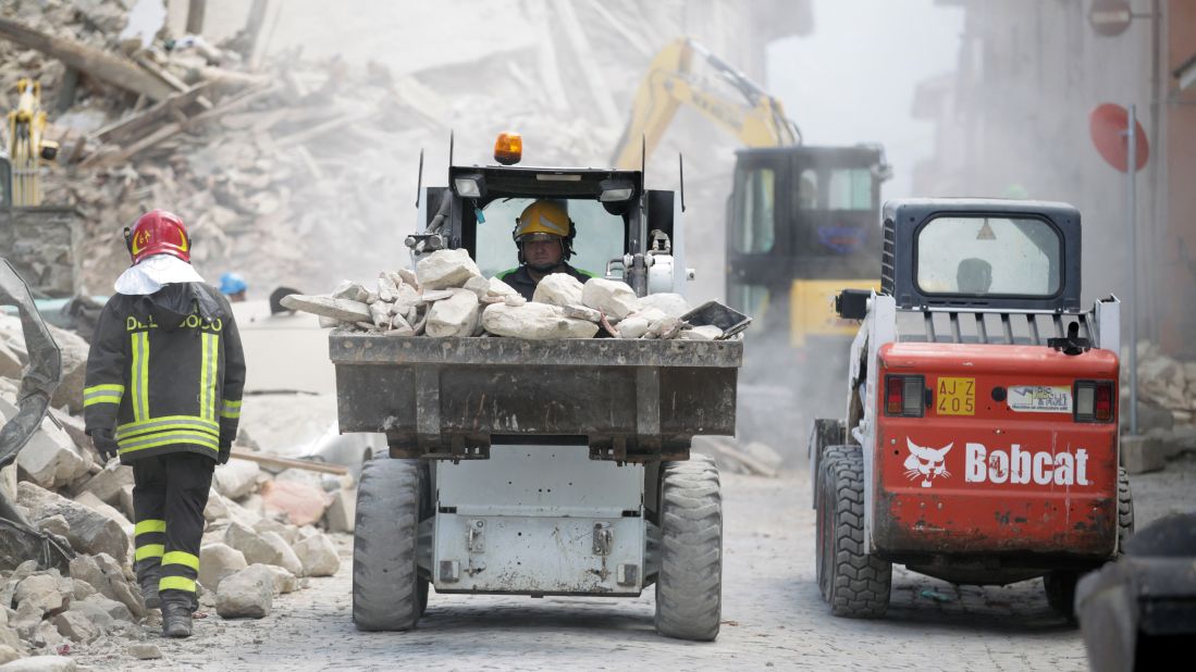A rescue worker drives a truck of rubble as cleanup operations begin in Amatrice.