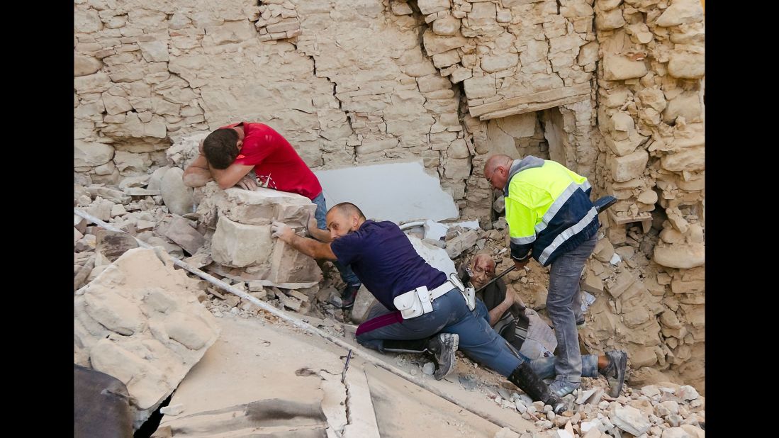 A man cries as another injured man is helped in Amatrice.