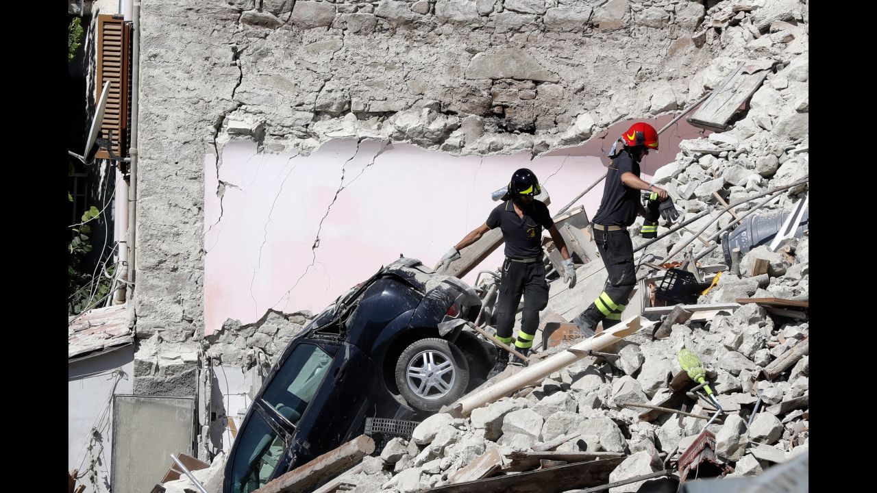 Rescuers make their way through destroyed houses in Pescara del Tronto on Thursday, August 25. It's unclear how many people remain trapped under debris.