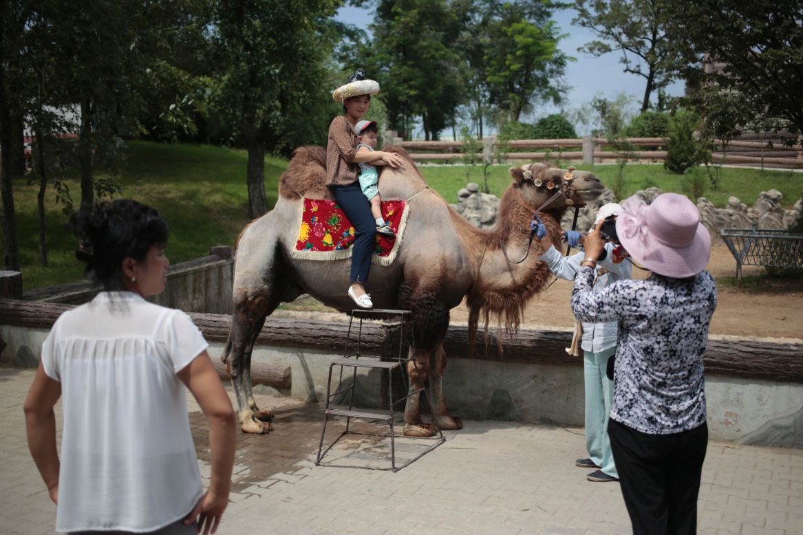 A North Korean and her son pose for a photo on the back of a camel at the newly opened North Korean zoo.