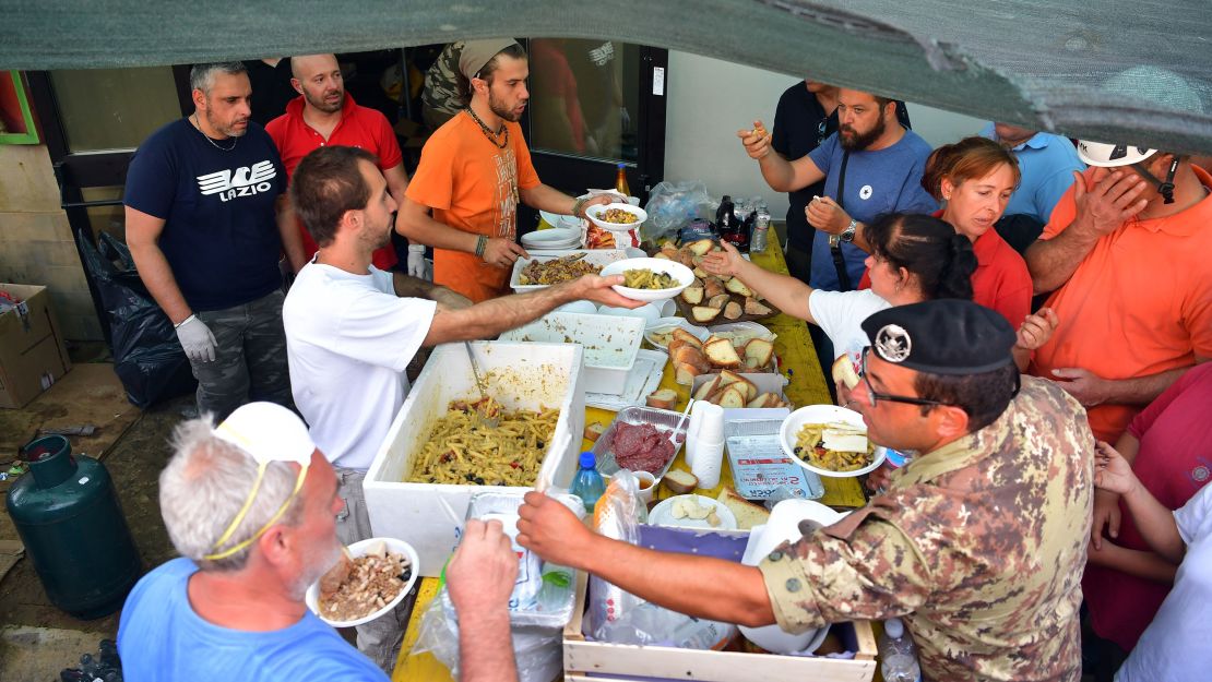 Emergency workers and earthquake survivors get food at a field kitchen in Amatrice on Thursday.
