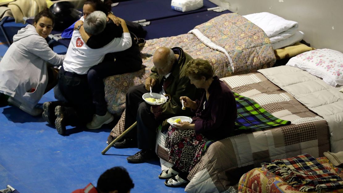 People prepare to spend the night Thursday in a makeshift camp set up in a gym in Amatrice.