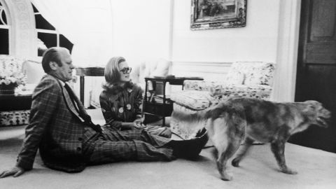 Ford sits with his daughter Susan on the floor of the White House's Great Hall, watching their pet golden retriever Liberty, circa 1978.