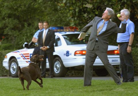 President Bill Clinton tosses a tennis ball for his dog, Buddy, at the White House on July 14, 1999.