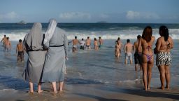 Two Polish nuns look at people bathing as hundreds of thousands of young Catholic pilgrims attending World Youth Day (WYD) start gathering at Copacabana beach in Rio de Janeiro for a prayer vigil with Pope Francis, on July 27, 2013. In a speech to Brazil's political, religious and civil society leaders earlier, Pope Francis said a "constructive dialogue" was needed to confront the country's social turmoil, referring to the massive street protests that rocked Brazil last month to demand an end to corruption and better public services.  AFP PHOTO / YASUYOSHI CHIBA        (Photo credit should read YASUYOSHI CHIBA/AFP/Getty Images)
