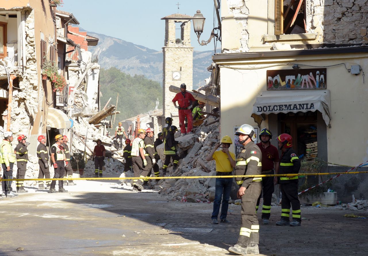 Firefighters and rescue workers stand near the damaged Sant'Agostino church and a destroyed ice cream shop in the Italian village of Amatrice on Friday, August 26.