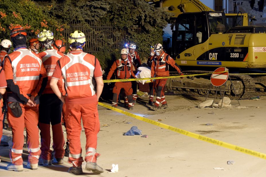 Rescuers of the Italian Red Cross carry the body of a victim in Amatrice, Italy, on Friday, August 26.