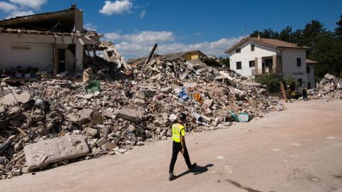 An emergency responder passes by the rubble of the building in Amatrice where Roberto Partenza and his family lived before the earthquake struck in the pre-dawn hours of Wednesday, August 24.