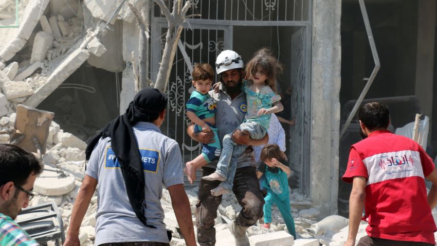 A Syrian rescue worker carries children in the Maadi district of eastern Aleppo after regime aircrafts reportedly dropped explosive-packed barrel bombs on August 27, 2016. 



 
At least 15 civilians were reported killed when two bombs fell several minutes apart, near a tent where people were receiving condolences for those killed this week.


 / AFP / AMEER ALHALBI        (Photo credit should read AMEER ALHALBI/AFP/Getty Images)