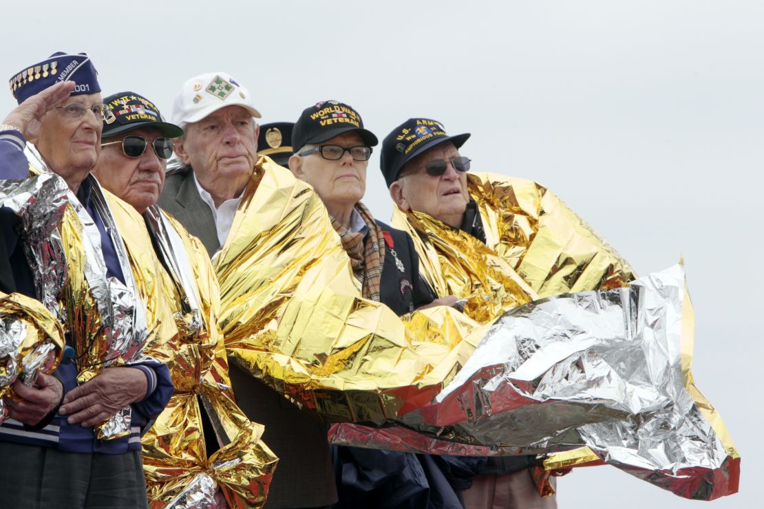 U.S. veterans use space blankets to keep warm at a D-Day commemoration in Normandy, France.  