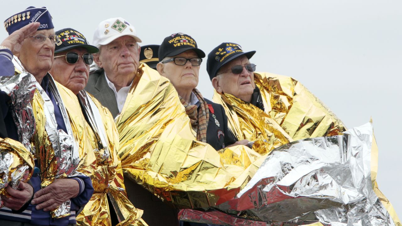 U.S. veterans use space blankets to keep warm at a D-Day commemoration in Normandy, France.