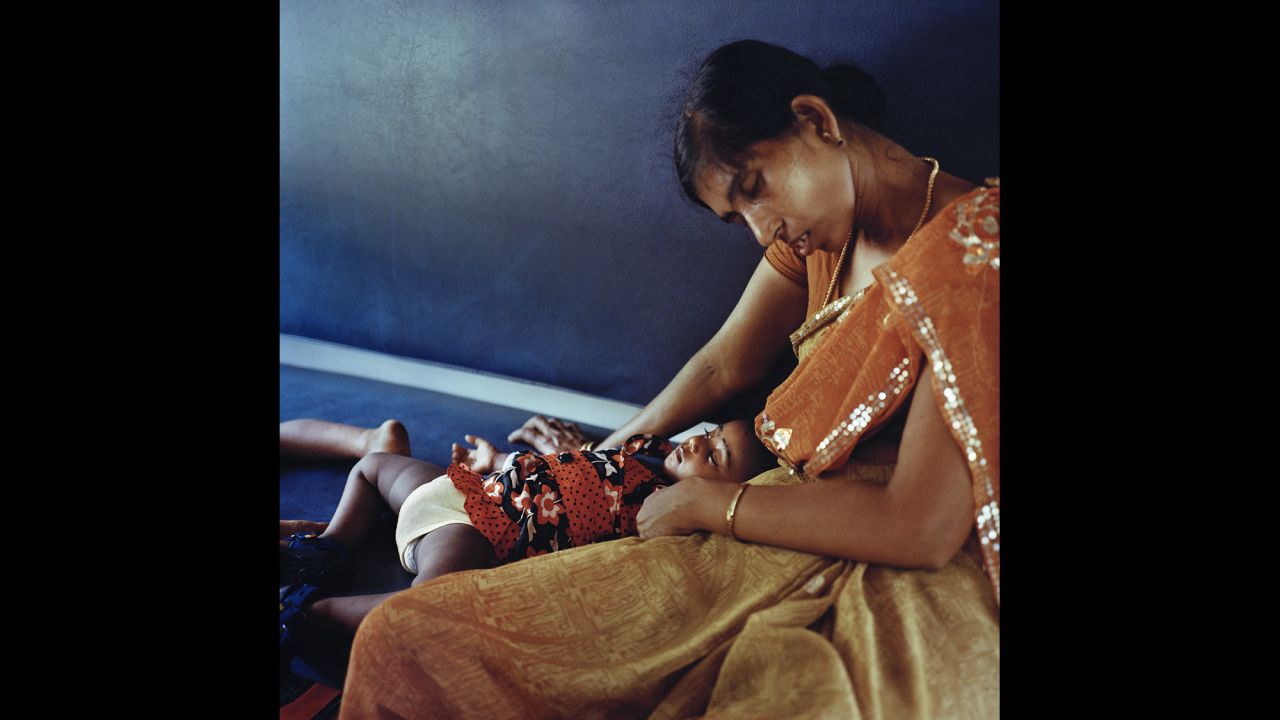 A mother rests with her baby on the third and final day of their train trip to Kerala.