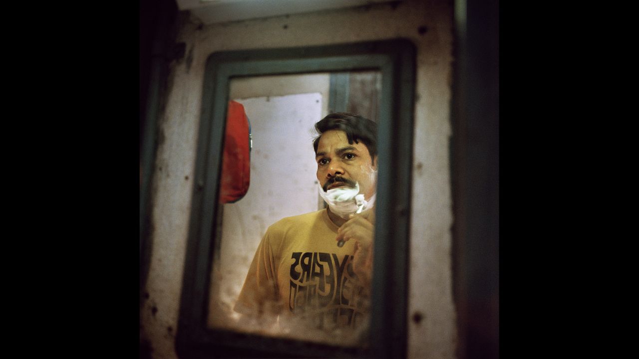 A passenger shaves before his train arrives at his final destination in Kerala. Many passengers spend several days on the train with no access to showers, and they must share common spaces such as a bathroom.