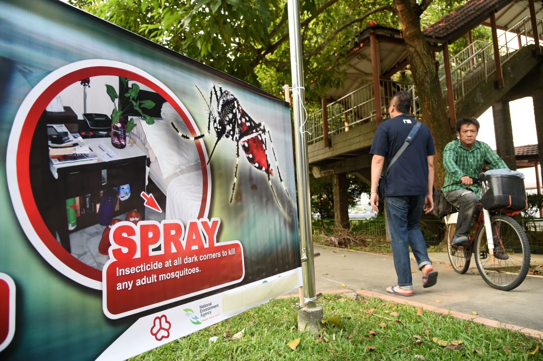 Residents are seen walking past a public service announcement banner against the spread of Aedes mosquitoes, a carrier for the Zika virus, at a residential block at Aljunied Crescent neighbourhood in Singapore on August 29, 2016.