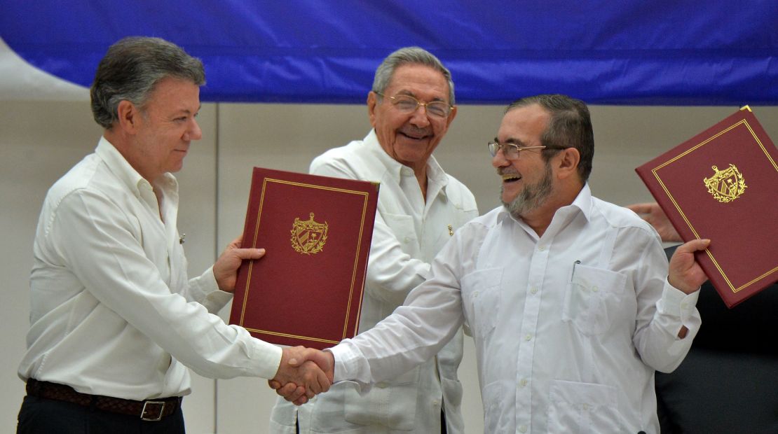 President Santos, left, shakes hands with FARC Leader Rodrigo Londoño Echeverri in Havana, as Cuban President Raul Castro looks on.