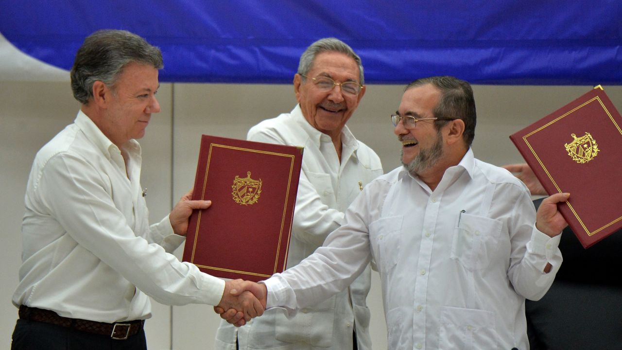 President Santos, left, shakes hands with FARC Leader Rodrigo Londoño Echeverri in Havana, as Cuban President Raul Castro looks on.