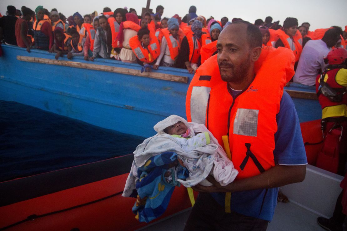 A man carries his 5-day-old son after being rescued from a crowded wooden vessel in the Mediterranean sea. The pair were fleeing from Libya.