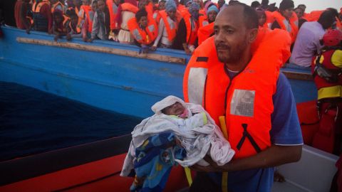 A man carries his 5-day-old son after being rescued from a crowded wooden vessel in the Mediterranean sea. The pair were fleeing from Libya.
