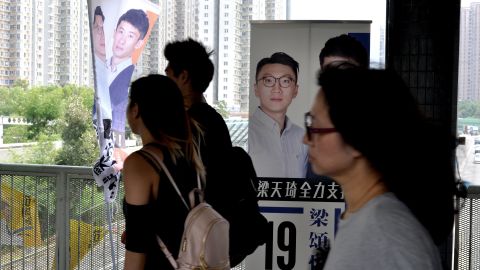 Commuters walk past signs bearing Edward Leung's face in Hong Kong's New Territories East constituency.