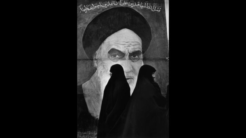 Women in Tehran, Iran, walk in front of a mural of Ayatollah Ruhollah Khomeini.