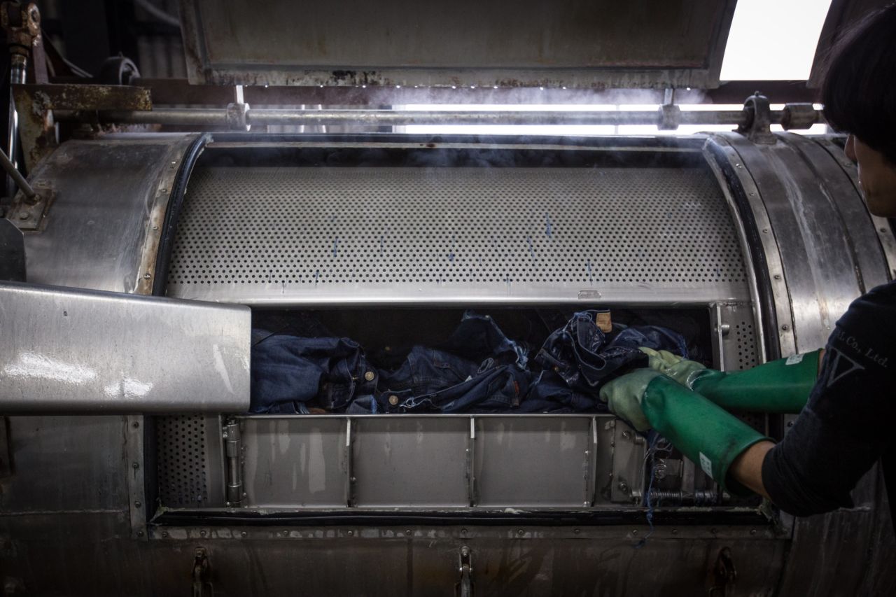 Here, an employee uses an vintage machine to lightly bleach the jeans after they have been dyed. 
