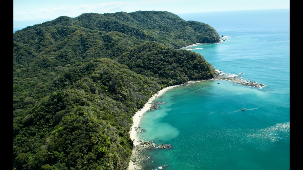Lush jungle-covered mountains stretch out into the Gulf of Nicoya next to the rocky and sandy beach of Ballena Bay in Costa Rica.