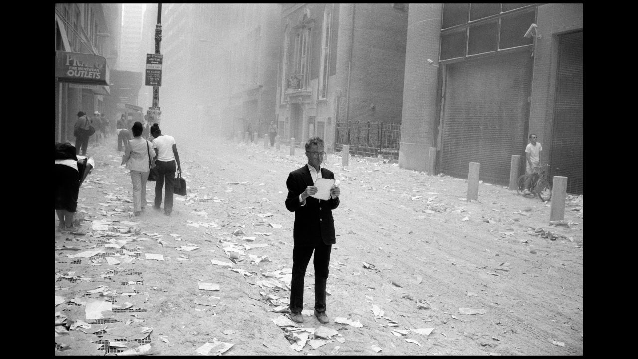 A dazed man picks up a paper that was blown out of the towers in this image by Magnum's Larry Towell. 