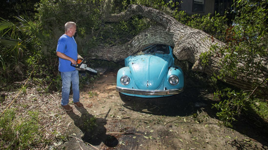 Tom Reams looks at a tree that fell on his house and his daughter's car in Alligator Point, Florida.