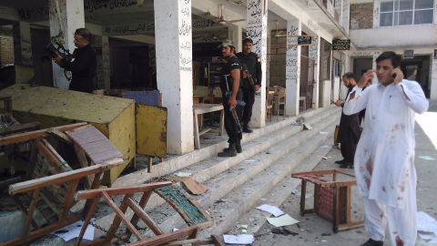 Pakistani police officials inspect the site of a suicide bomb attack at a district court in Mardan.