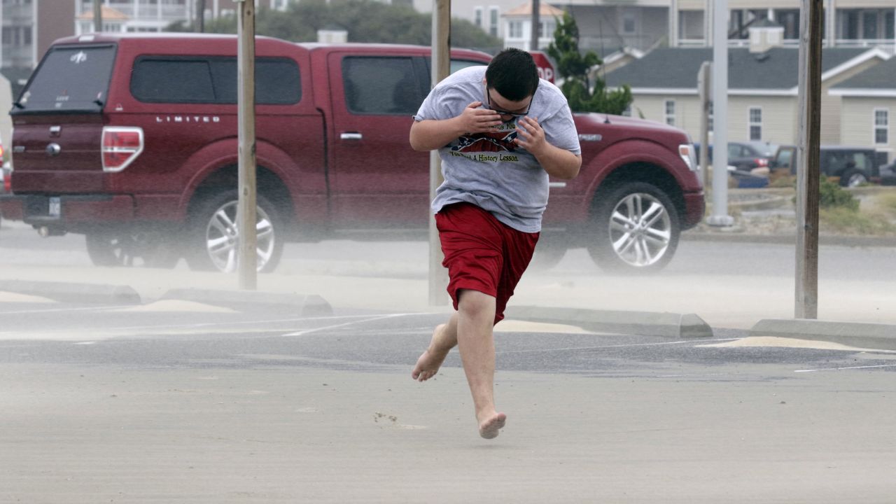 Eli White covers his face from the blowing sand in Nags Head, North Carolina, Saturday, September 3, as the tail of Tropical Storm Hermine passes the Outer Banks. Hermine hit Florida's Gulf Coast on Friday as a hurricane but has since weakened.