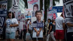 TOPSHOT - A campaigner (C) stands behind a placard of Baggio Leung, 30, one of three candidates from new party Youngspiration, during the Legislative Council election in Hong Kong on September 4, 2016.
Young Hong Kong independence activists calling for a complete break from China stood in major elections for the first time on September 4, the biggest vote since 2014 pro-democracy rallies.  / AFP / Anthony WALLACE        (Photo credit should read ANTHONY WALLACE/AFP/Getty Images)