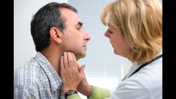 female doctor touching the throat of a patient in the office; Shutterstock ID 206475955