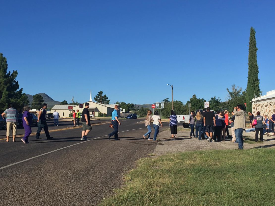 People cross a street as Alpine High School is evacuated following a shooting there Thursday morning.