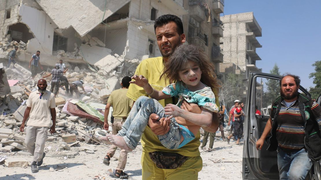 A Syrian man carries a wounded child in eastern Aleppo last month.