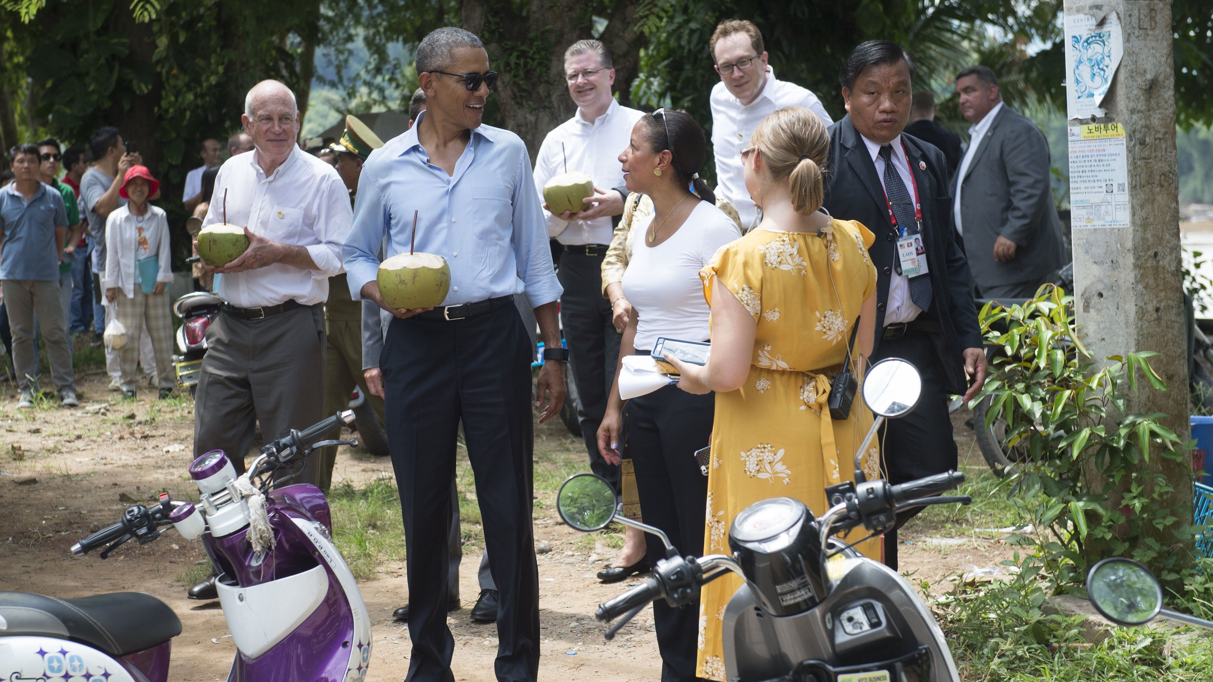 US President Barack Obama drinks from a coconut (2nd L) with US Ambassador to Laos Daniel Clune (L) as he makes a surprise stop for a drink alongside the Mekong River in Luang Prabang on September 7, 2016.
