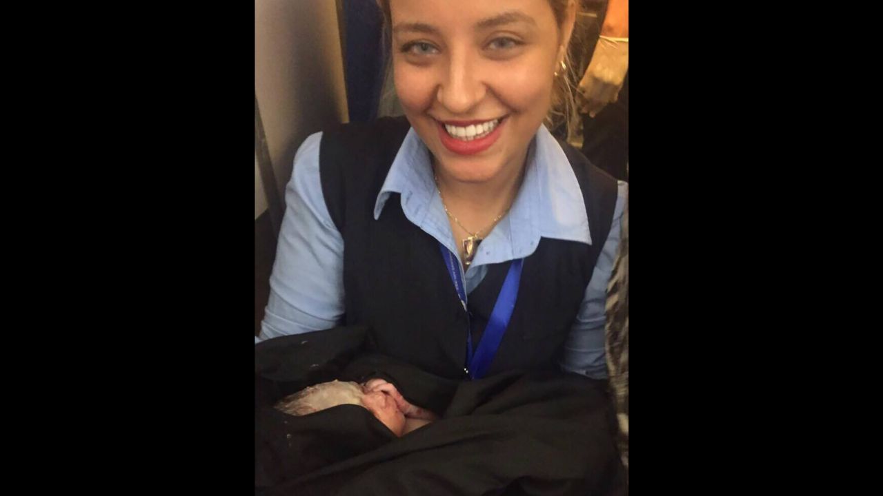 The new born baby boy is pictured in the arms of one of the cabin crew. 