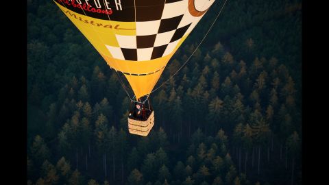 A hot air balloon flies above a forest in Arnsberg, Germany, on Thursday, September 8. 