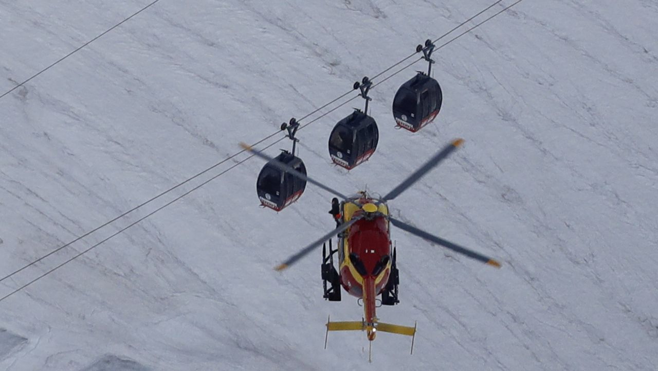 An EC-135 helicopter operated by the French Societe' Civile hovers, Friday, Sept. 9, 2016, near three cars of the Panoramic Mont Blanc cable car that stalled around 4 p.m. (1400 GMT) on Thursday, after its cables reportedly tangled. The cable car carrying tourists stopped working at high altitude over the Mont Blanc massif in the Alps on Thursday, prompting a major rescue operation and leaving 45 people trapped in midair overnight, France's interior minister said. (AP Photo/Luca Bruno)