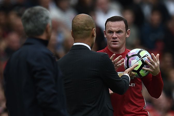 Manchester United's English striker Wayne Rooney (R) and Manchester City's Spanish manager Pep Guardiola clash on the touchline as Rooney tries to retrieve the ball.