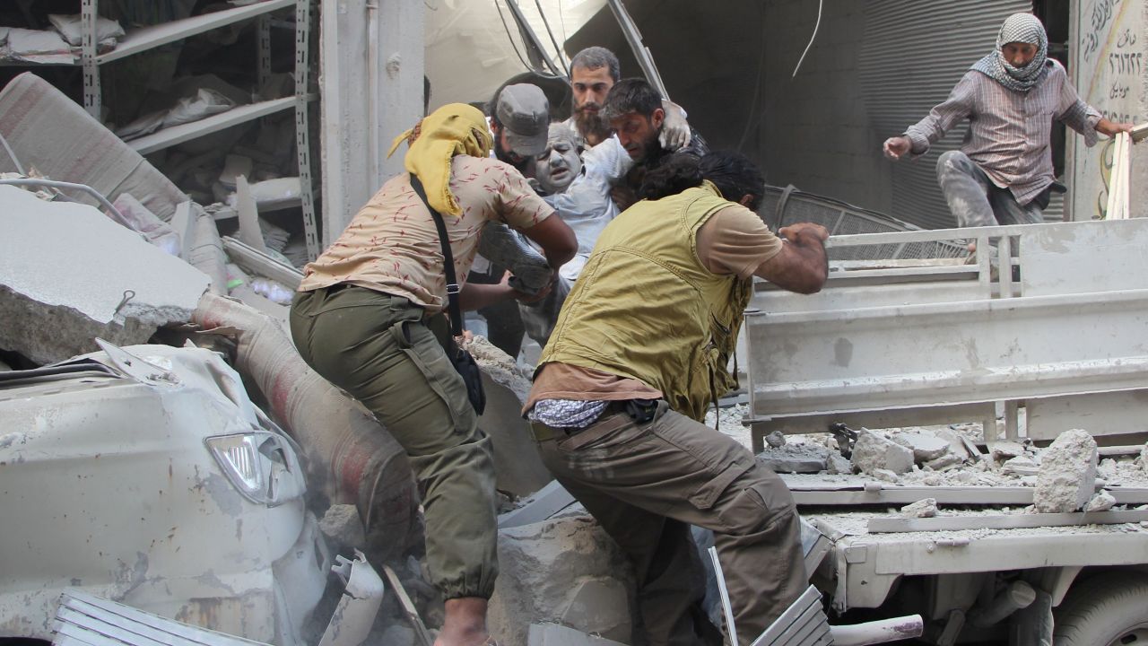 Syrian men evacuate a victim from the rubble of a building following an airstrike on the rebel-held northwestern city of Idlib on September 10, 2016.