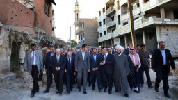 In this photo released by the Syrian official news agency SANA, Syrian President Bashar Assad, center, walks on a street with officials after performing the morning Eid al-Adha prayers in Daraya, a blockaded Damascus suburb, Syria, Monday, Sept. 12, 2016. Syrian President Bashar Assad says his government is determined to "reclaim every area from the terrorists, and to rebuild" the country. His remarks came just hours ahead of the start of a cease-fire brokered by the United States and Russia. (SANA via AP)