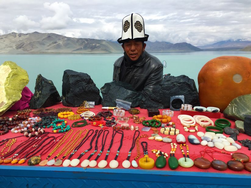 A vendor sells items beside the Karakul Lake.