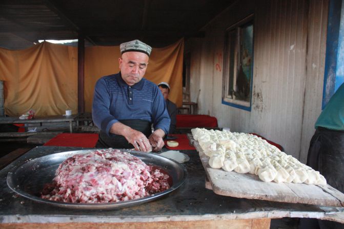 A man makes samsa -- bread parcels with diced lamb inside -- at the market. The parcels are baked inside a stone oven.