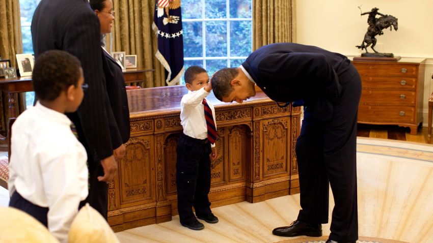WASHINGTON - MAY 8:  In this handout from the The White House, U.S. President Barack Obama bends over so the son of a White House staff member can pat his head during a visit to the Oval Office May 8, 2009 in Washington, DC.  (Photo by Pete Souza/The White House via Getty Images)