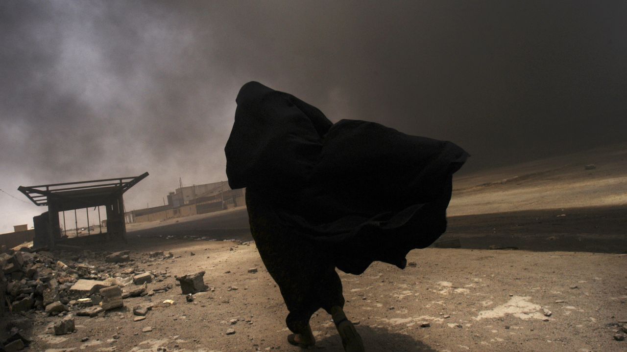 An Iraqi woman walks through a plume of smoke rising from a massive fire at a liquid gas factory as she searches for her husband in the vicinity of the fire in Basra, Iraq, May 26, 2003.  The fire was allegedly started by looters picking through the factory, and residents in the vicinity feared the explosion of the four liquid gas tanks on the premisis.   Weeks after the end of the war, looting continues to be one of the main problems for both Basra and Bagdad cities as coalition forces struggle to get life back to normal.